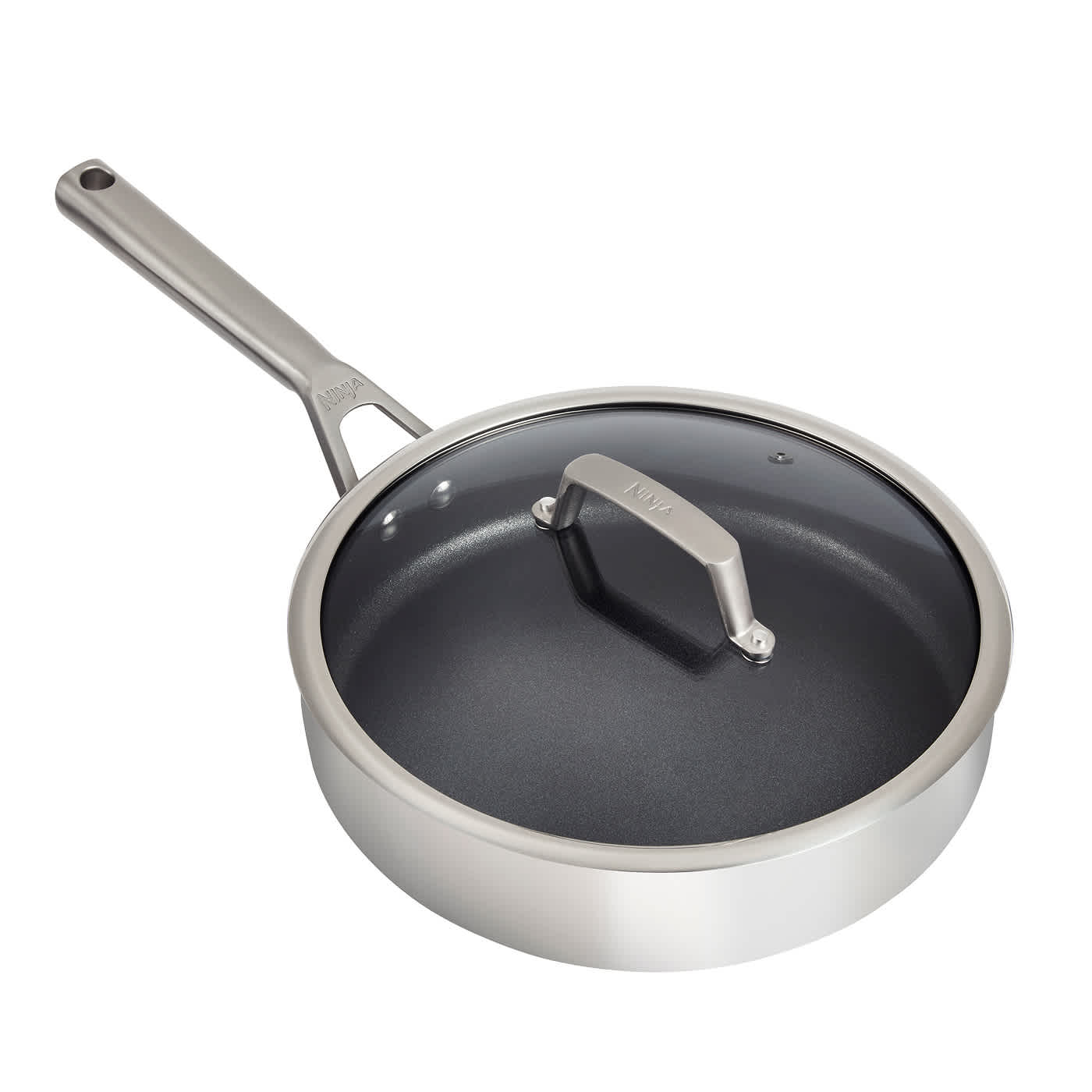 A Ninja stainless steel sauté pan with black interior and a glass lid.