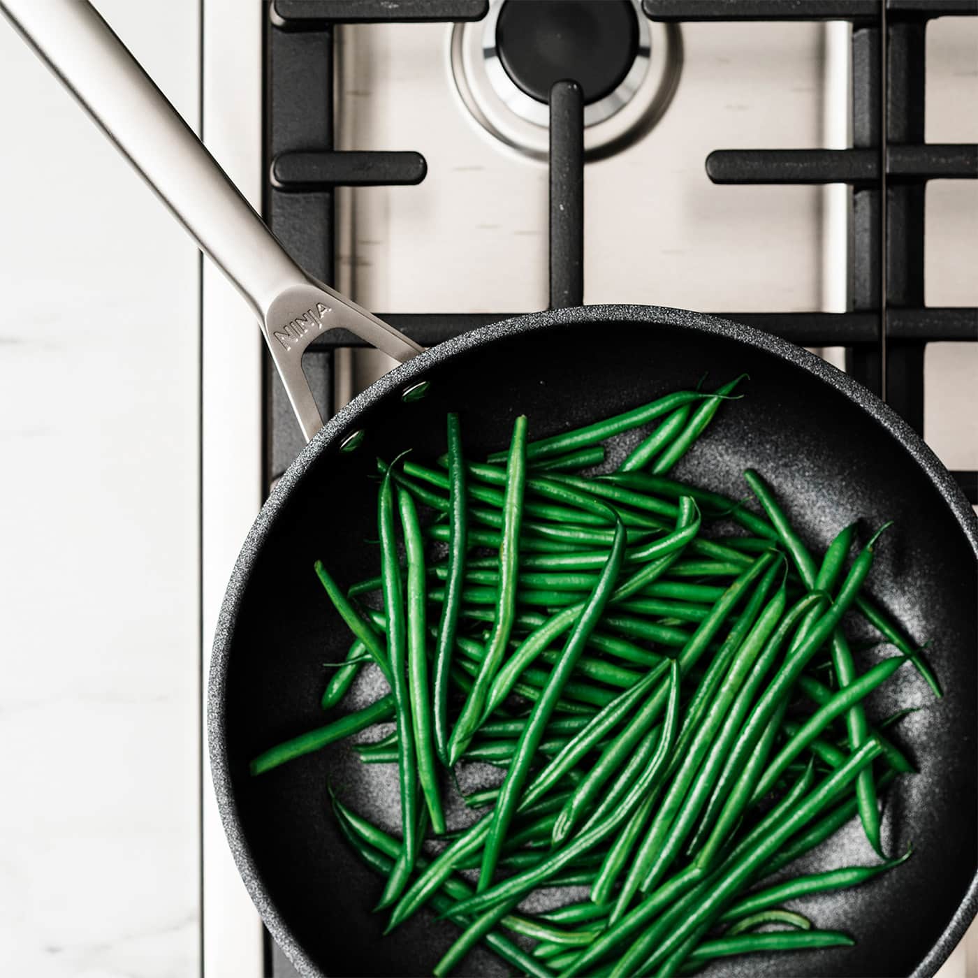 Image of Ninja sauce pan on a gas hob with green beans.